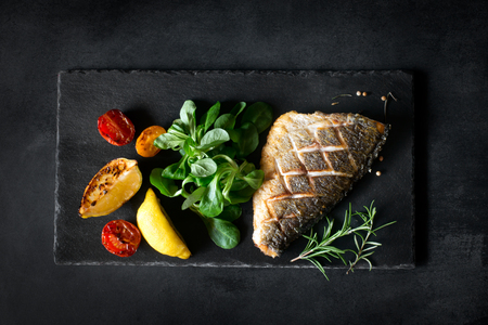 Baked dorado with fresh salad and vegetables. Top viewの写真素材