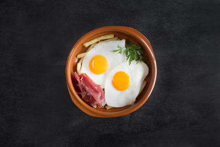 Traditional spanish lunch - fried eggs with french fries, cured pork slices jamonの写真素材