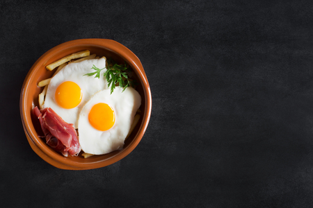 Traditional american lunch - fried eggs with french fries, cured pork slices jamon. Top view with copy spaceの写真素材