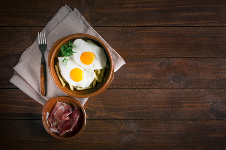 Traditional spanish lunch - fried eggs with french fries, cured pork slices jamon. Copy space for your textの写真素材