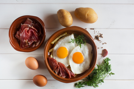 Traditional spanish lunch - fried eggs with french fries, cured pork slices jamonの写真素材