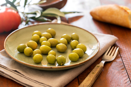 Fresh green olives on the rustic plateの写真素材