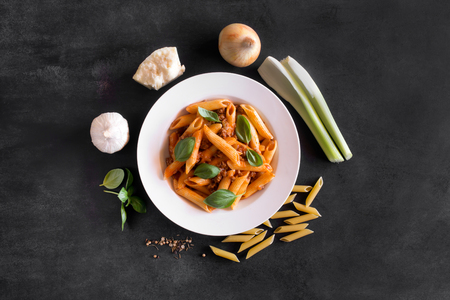 Italian Penne pasta with Bolognese sauce. Top view on the black backgroundの写真素材