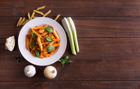 Italian Penne pasta with Bolognese sauce on the brown wooden tableの写真素材