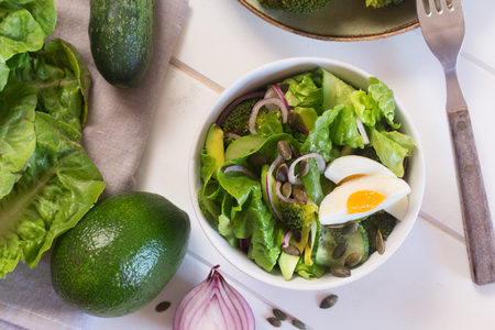 Healthy lunch- salad prepared with fresh green leaves, onion and boiled chicken eggの写真素材