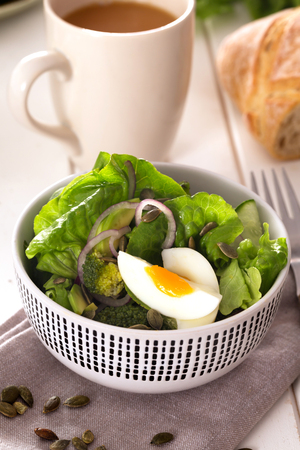 Healthy lunch- salad prepared with fresh green leaves, onion and boiled chicken eggの写真素材