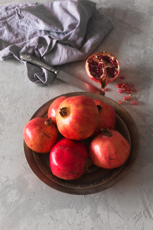 Ripe pomegranate on a metallic plate on a dark background. Vertical orientationの写真素材