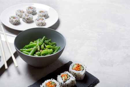 Traditional japanese and chinese food. Steamed green beans and sushi rollsの写真素材