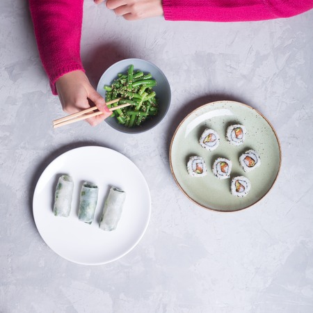 Woman takes the sushi rolls using chopsticks. Top viewの写真素材