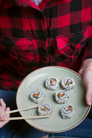 Woman takes the sushi rolls from plate using chopsticks. Top viewの写真素材