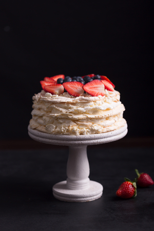 Strawberry pavlova cake on a black background and tableの写真素材
