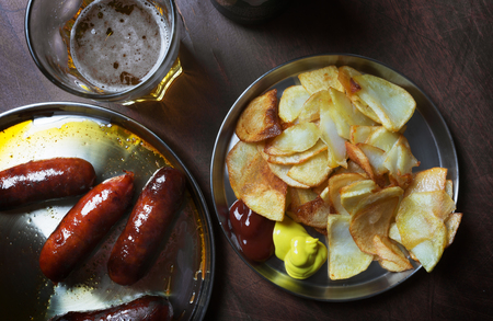 Grilled sausages prepared on grill. Served with fried in a frying pan potatoes, ketchup and mustardの写真素材