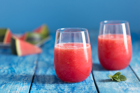 Fresh watermelon smoothie in two glasses on a blue wooden rustic backgroundの写真素材