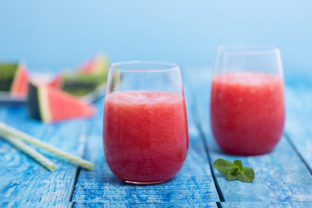 Fresh watermelon smoothie in two glasses on a blue wooden rustic backgroundの写真素材