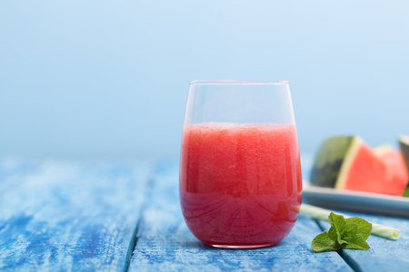 Fresh watermelon smoothie in a glass on a blue wooden rustic background with copyspaceの写真素材