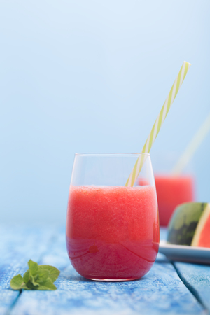 Fresh watermelon smoothie in two glasses on a blue wooden rustic background. Photo with copyspace, vertical orientation.の写真素材