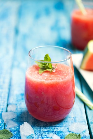 Fresh watermelon smoothie in two glasses on a blue wooden rustic background. Closeup shot.の写真素材