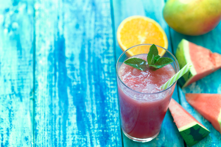 Fresh multifruit smoothie in a glasses with a straw on a blue wooden rustic backgroundの写真素材