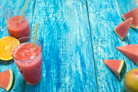 Fresh multivitamin smoothie in two glasses with straws on a blue wooden rustic backgroundの写真素材
