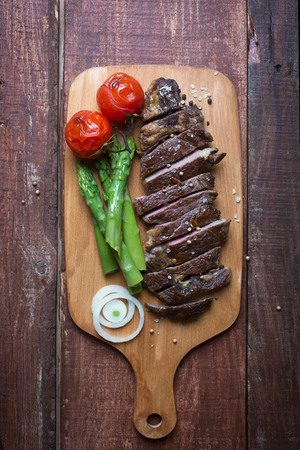 Grilled beef steak on a light chopping board wooden rustic backgroundの写真素材
