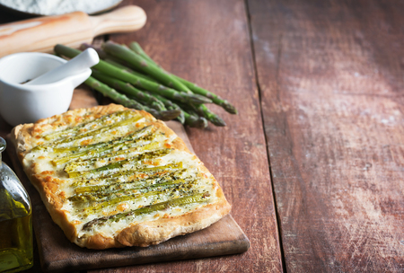 Asparagus green pizza with herbs and mozzarella on the wooden rustic backgroundの写真素材