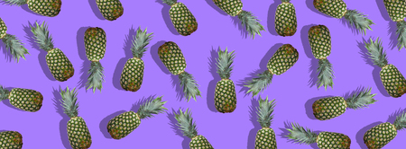 Fresh pineapples on the violet colorful background. Creative image for modern designers. Food collageの写真素材