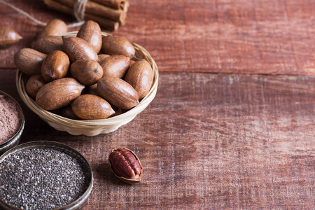 Pecan nuts, chia seeds and cocoa in a bowls on a wooden table. Tipical superfoods for healthy eatingの写真素材