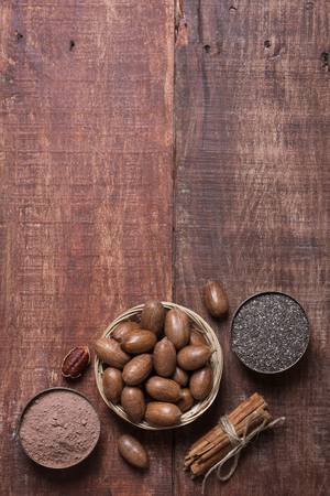 Pecan nuts, chia seeds and cocoa in a bowls on a wooden table. Tipical superfoods for healthy eating. Vertical photoの写真素材