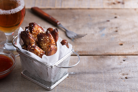 Spicy chicken wings prepared on barbecue on the wooden table with glass of beerの写真素材