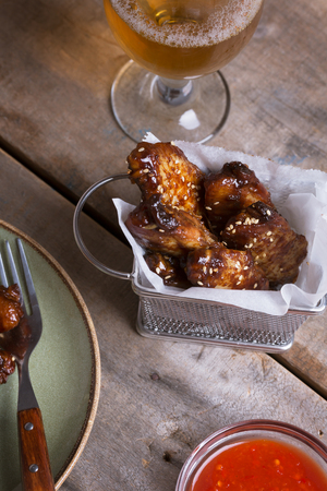 Spicy chicken wings prepared on barbecue on the wooden table with glass of beerの写真素材