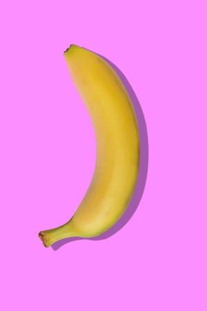 Yellow banana on pink pastel background with a shadowの写真素材