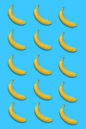 Yellow bananas pattern isolated on blue backgroundの写真素材