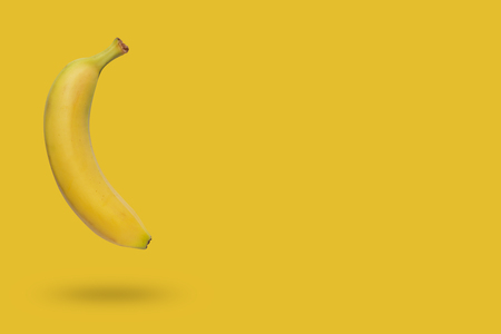 Banana isolated on yellow background with a shadowの写真素材