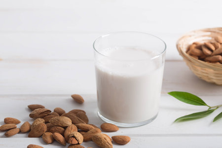 Almond milk in a glass on a white wooden tableの写真素材