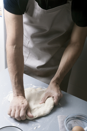 Man on the home kitchen prepares the pizza dough with flourの写真素材