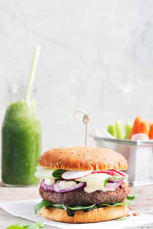 Veggie bean and quinoa burger with fresh vegetables on concrete backgroundの写真素材