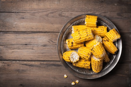 Grilled corn cobs on the metallic rustic plate. Top view with free spaceの写真素材