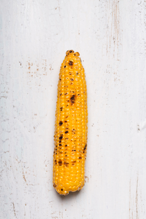 Single grilled corn cobs on the white woodenの写真素材