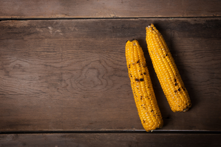 Two Grilled corn cobs on the brown rusticの写真素材