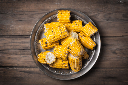 Grilled corn cobs on the brown rustic plate with copy space.の写真素材