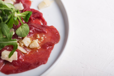 Beef carpaccio with arugula salad, parmesan and sauce on the white plateの写真素材