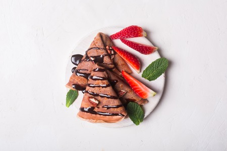 Traditional French crepes cooked with chocolate. Decorated with mint and strawberriesの写真素材