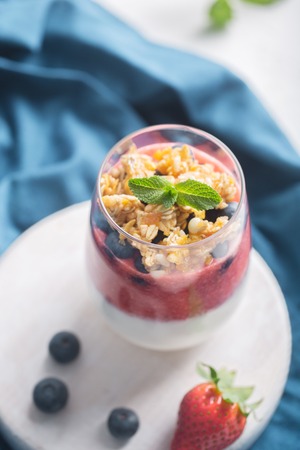 Glass of yogurt or panna cotta with strawberry mousse and granola on a whiteの写真素材