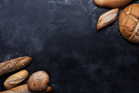 Fresh bread on black table. Top view with copy space, horizontal orientation