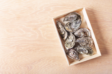 Oysters on box on wooden background, toned image. Shellfish contains a mass of beneficial micronutrients and vitamins that beneficially affect the entire bodyの写真素材