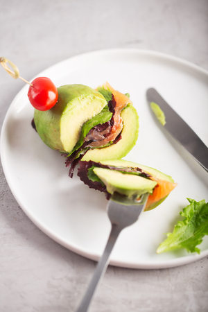 Cutted organic raw avocado burger with salted salmon and fresh vegetables.の写真素材