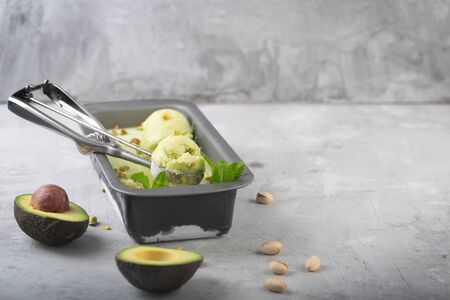 Homemade organic avocado ice cream in metallic container on a gray background