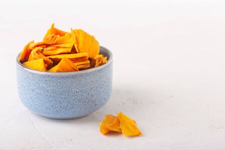 Mango chips in a blue bowl and pieces of this fruits on a table. Horizontal orientationの写真素材