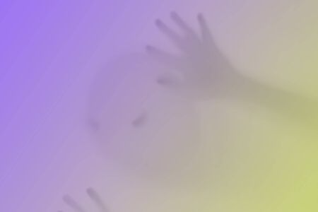 Halloween blurred background. A ghost resembling a pumpkin in color behind glass. Terrible and...