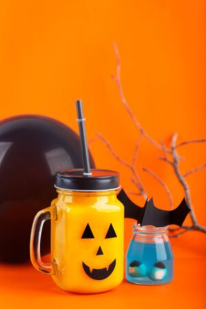 Halloween healthy pumpkin or carrot drinks in the glass jar on a orange backgroundの写真素材